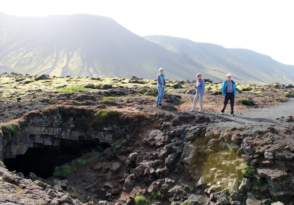 Laura, Günther and Marion standing at the entrance of a lava tube cave in Iceland