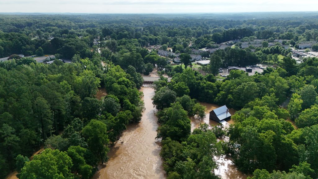 Aerial photo of river flooding park in foreground and neighborhood in background