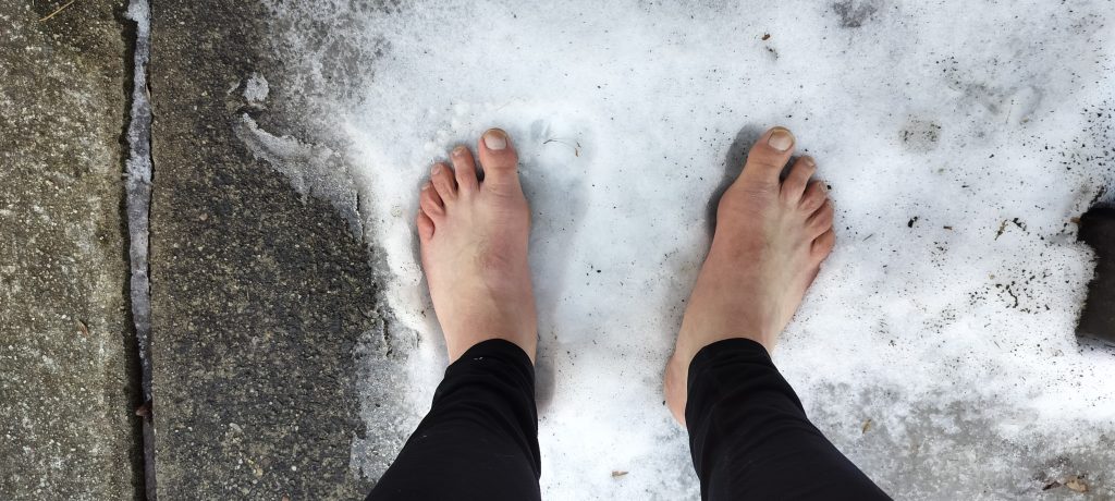 photo of bare feet in a patch of snow